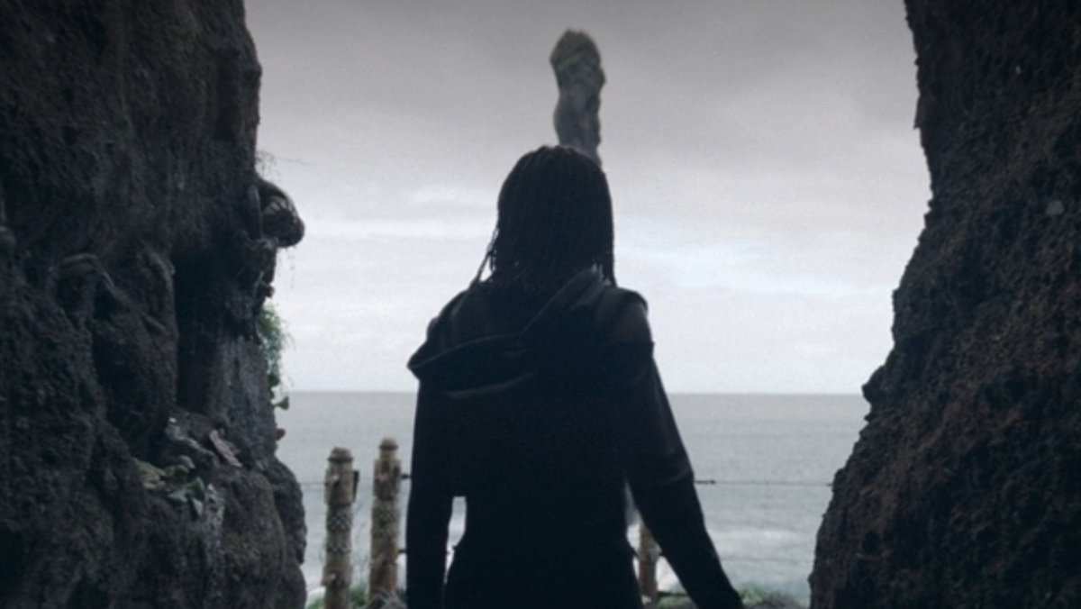 Osha stands in a cave entrance overlooking the ocean on The acolyte on Qimir's unknown planet that may be Ahch-to